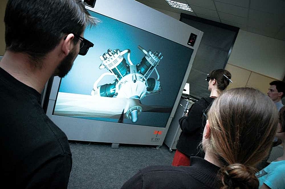 in Bildmitte ist die VR-Projektionswand zu sehen, darauf ist das Modell "Sternmotor" abgebildet, davor steht die Lehrende und am Bildrand vorn und rechts Studierende