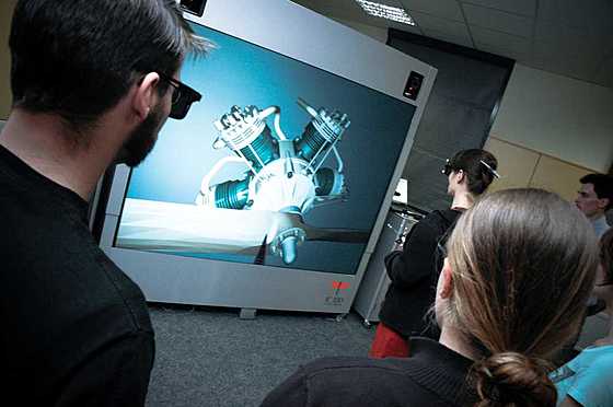 Modell "Sternmotor" an der Powerwall in Bildmitte ist die VR-Projektionswand zu sehen, darauf ist das Modell "Sternmotor" abgebildet, davor steht die Lehrende und am Bildrand vorn und rechts Studierende