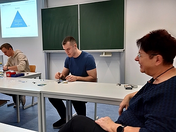 Zwei Studenten im Seminarraum sind mit einer Aufgabe beschäftigt