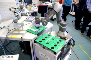 Arbeitsplatz im Labor, ein mobiler Roboter legt ein Werkstück auf den Tisch